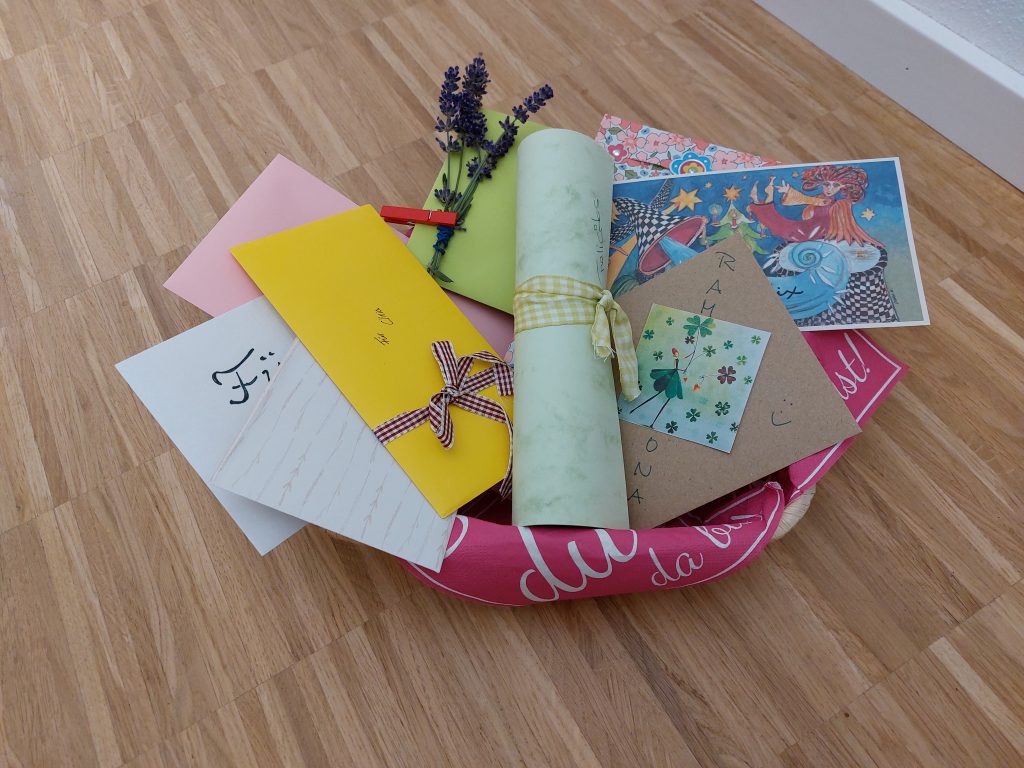 Bunter Korb gefüllt mit Briefen, Karten und einem kleinen Strauß Lavendel.