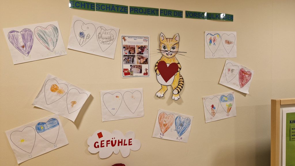 Bunte Kinderzeichnungen und herzförmige Plakate beim Projekt „Starke Kinderkiste“ mit dem Motto „Ich darf „Nein“ sagen!“ und grünem Banner.
